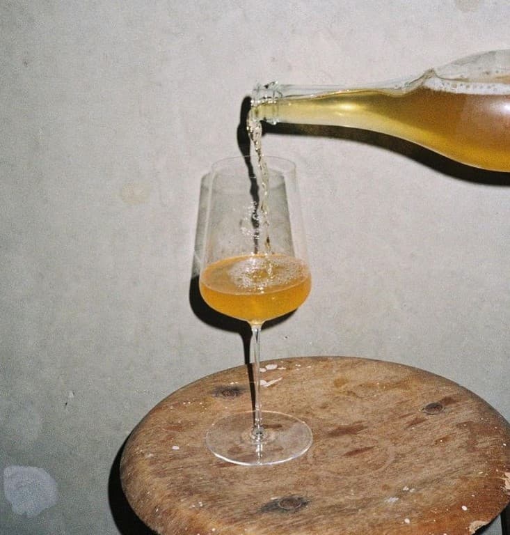 Kombucha servida en una copa de vino sobre un banco